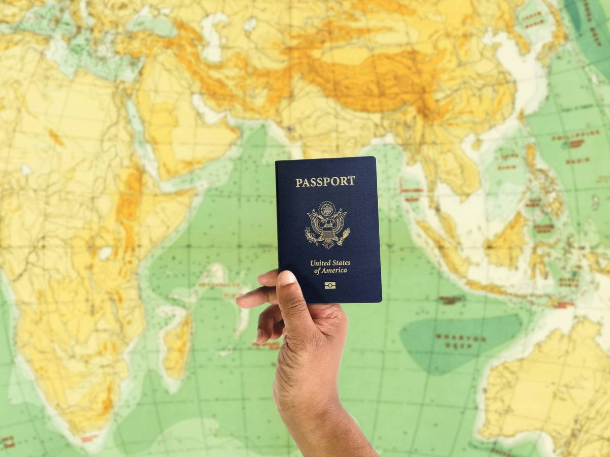 A person filling out paperwork at an airport counter while holding a passport.